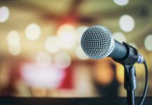 Lip-Sync SCANDAL Backfires — Kid Rock Fires Back Microphone with blurred lights in the background.