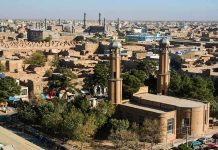 Axe-Wielding Men Storm Mosque Aerial view of a city featuring traditional buildings and minarets