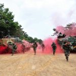 Soldiers running from armored vehicles with red smoke.