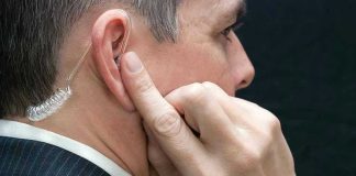 CIA Chief Faces Explosive Criminal Referral Man wearing an earpiece, touching his ear.