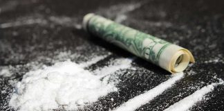 $6.4M Cocaine Stash Found in Oil Tanker Powder lines, rolled dollar bill on black surface.