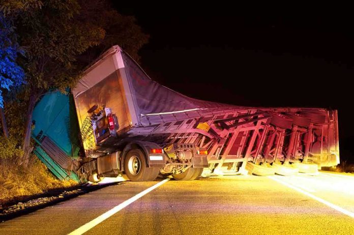 shutterstock_115026379 An overturned truck on the side of the road at night with emergency lights