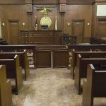 Treason Talk Explodes — Legal Reality Says Otherwise Interior view of an empty courtroom with wooden benches and a judges bench