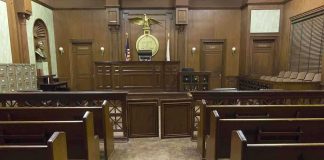 Treason Talk Explodes — Legal Reality Says Otherwise Interior view of an empty courtroom with wooden benches and a judges bench
