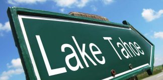 A green directional sign pointing to Lake Tahoe against a blue sky