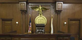 Insurance Cash, Dead Family — What Broke Him? Judges bench in an empty courtroom, scales emblem above.