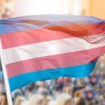 Governor’s Veto Sparks Gender-Identify Uproar Transgender pride flag waving at outdoor event.