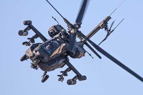 shutterstock_2396101519 An Apache helicopter flying in the sky with visible rotor blades