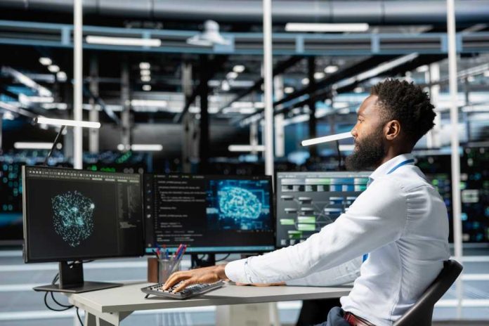 shutterstock_2634479529 A man working at a computer workstation with multiple screens displaying data visualizations