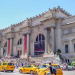 Grand museum facade with columns and busy street with taxis