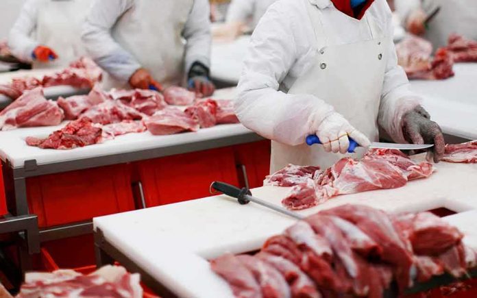 shutterstock_1701927493 Butchers cutting raw meat on processing line