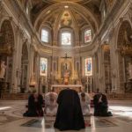 Individuals kneeling in prayer inside a grand cathedral