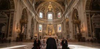 Individuals kneeling in prayer inside a grand cathedral