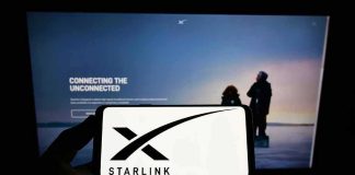 Smartphone showing Starlink logo in front of a computer screen
