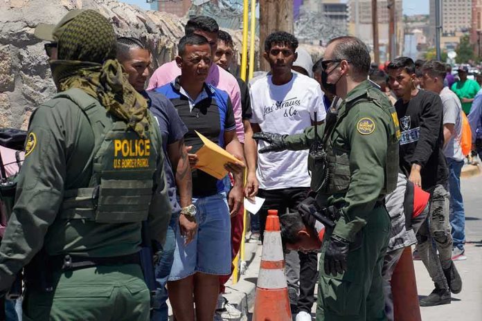 Border patrol officers speak with a line of people outdoors