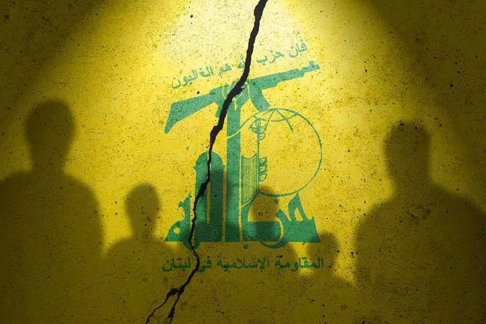 shutterstock_2373422413-1 Hezbollah flag graphic with crack and silhouetted figures