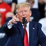 Trump Teases MASSIVE Iran Strike Man in suit pointing, speaking at a rally.