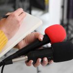 U.S. Military Expands Philippines War Games to Deter China Journalist holding two microphones while writing in a notebook