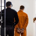 State’s 13th Execution of 2026 Prisoner in orange jumpsuit handcuffed and escorted by officer