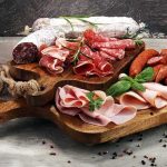 Charcuterie board with assorted cured meats and herbs