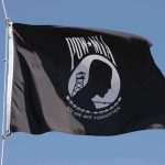 Captured Navy Pilot Made a Defiant Choice Under Torture POW MIA flag waving against a blue sky
