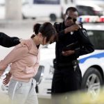 AI Match Put Grandmother Behind Bars for Months Police officers detain a woman beside a patrol car