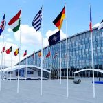 Row of national flags outside a modern glass building