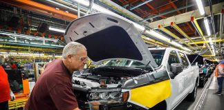 factory worker assembling a pickup truck on an automotive production line