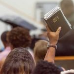 Devil Horns and a Torn Bible on 9/11 in New York Hand holding a Bible in a crowded church service
