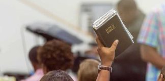 Devil Horns and a Torn Bible on 9/11 in New York Hand holding a Bible in a crowded church service
