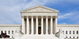 Justice Alito Steps Aside From Major Supreme Court Case Front view of the Supreme Court building with large columns and steps under a blue sky
