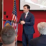 The Democratic Civil War Just Got Personal Speaker in a navy suit addressing an audience at a podium