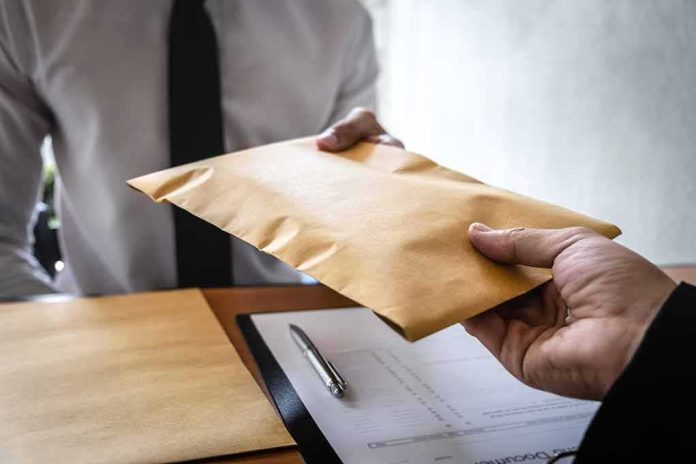shutterstock_1383868892 Hands exchanging a brown envelope across a desk