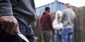 Person holding a folding knife near a group of people in an alley
