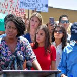 Ayanna Pressley speaking at a podium during an outdoor press event