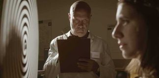 Scientist with clipboard observes woman beside spiral target