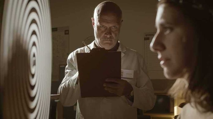 shutterstock_1527380264 Scientist with clipboard observes woman beside spiral target
