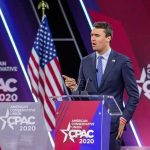 New Report Finds Major Failures Before Campus Killing Speaker in suit at CPAC podium on stage