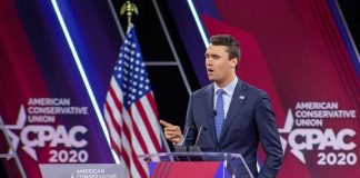 New Report Finds Major Failures Before Campus Killing Speaker in suit at CPAC podium on stage
