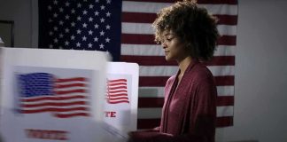 Former GOP Senior Advisor Says He’s Voting for a Democrat Voter at a polling booth with an American flag backdrop