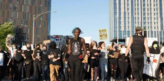 Protesters march on a city street holding signs