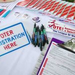 Trump Bets Big on Pillow Guy Voter registration table with forms, pens, and informational materials
