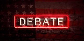 Neon sign reading debate on a brick wall