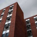 Silent Heatwave Body Count Brick apartment buildings with window air conditioners under cloudy sky