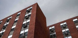 Brick apartment buildings with window air conditioners under cloudy sky