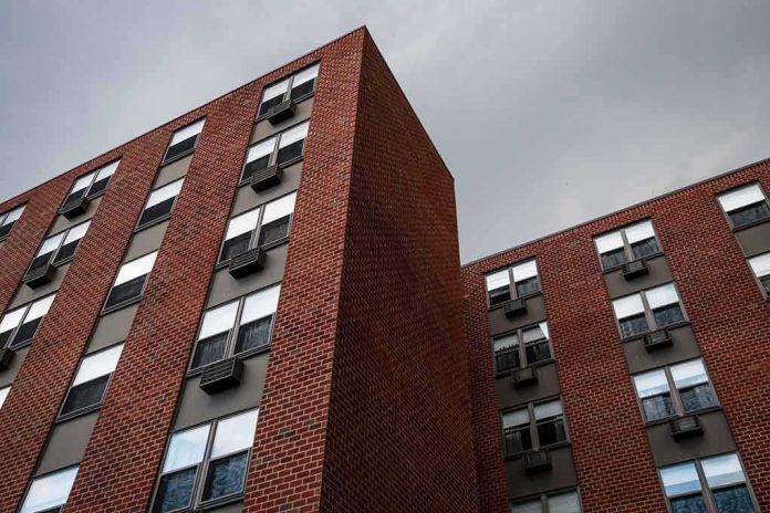 shutterstock_1804030036 Brick apartment buildings with window air conditioners under cloudy sky
