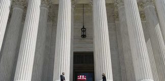 Flag-draped casket on courthouse steps between towering columns
