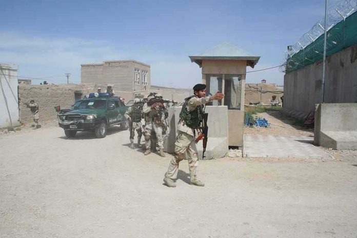 Armed soldiers patrol near a guard post outside a walled compound