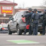 Gunfire Chaos At In-N-Out Police officers gather beside a patrol SUV at a taped-off scene