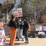 protesters with signs at an outdoor student debt rally